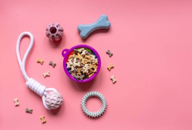 Lastik toplar, yüzükler, evcil hayvanlar için atıştırmalıklar. Köpekler için çok renkli toplar ve pembe arka planda kemik atıştırmalıkları. Oyuncaklar, toplar, kemikler, oyun ve antrenman için.