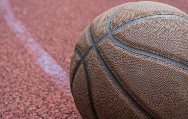 Kırmızı sahada yakın plan basketbol topu. Sokakta ya da kapalı sahada basketbol. İnsansız spor malzemeleri. Şablon, spor arka planı