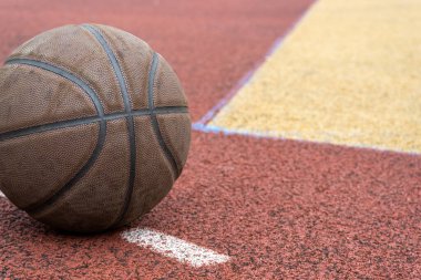 Kırmızı sahada yakın plan basketbol topu. Sokakta ya da kapalı sahada basketbol. İnsansız spor malzemeleri. Şablon, spor arka planı