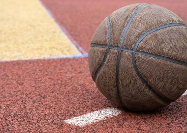 Kırmızı sahada yakın plan basketbol topu. Sokakta ya da kapalı sahada basketbol. İnsansız spor malzemeleri. Şablon, spor arka planı