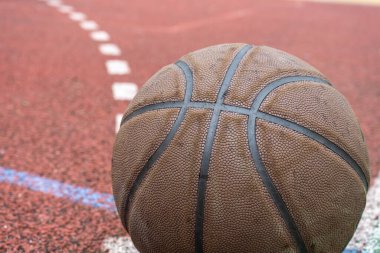 Kırmızı sahada yakın plan basketbol topu. Sokakta ya da kapalı sahada basketbol. İnsansız spor malzemeleri. Şablon, spor arka planı