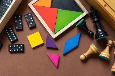 Different desktop games, figures, dices, parts on the brown table. Home entertaiment, indoor games