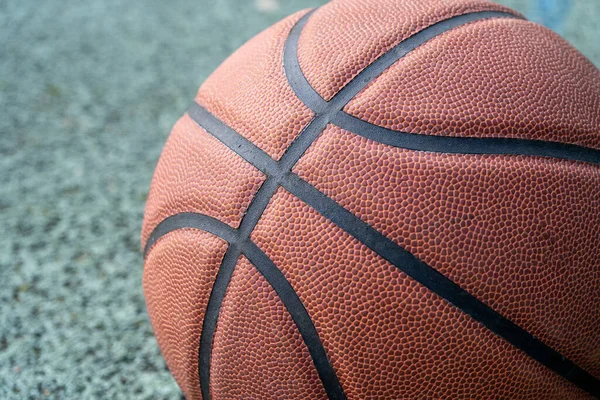 Orange basketball ball on the ground. Close-up ball on the red court. Basketball on the street or indoor court. Sports gear without people. Minimalism. Template, sport background
