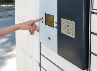 Man opening a door of post office box on the city street and receive a parcel. Man carrying box from post office delivery