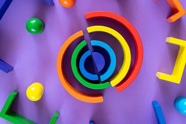 Multicolored abstract rainbow background. Wooden kids toys on violet paper. Educational toys blocks, rainbow. Toys for kindergarten, preschool or daycare.