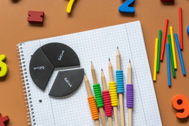 Set of supplies for mathematics and for school. Fractions, rulers, pencils, notepad on brown background, Back to school, fun education concept