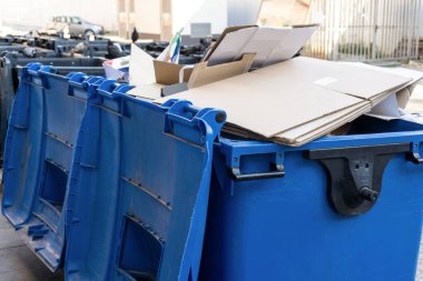 Şehirde içinde karton olan mavi çöp tenekesi. Atıkları ayır, çevre kavramını koru. Atıkları ayır, kasabadaki çöpleri ayır. Kapat.