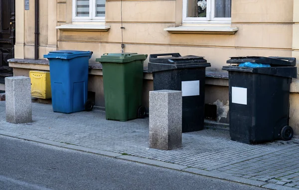 Black, blue, yellow, green garbage containers in city. Separate waste, preserve the environment concept. Segregate waste, sorting garbage bins. Colored trash cans with paper, plastic, glass, organic