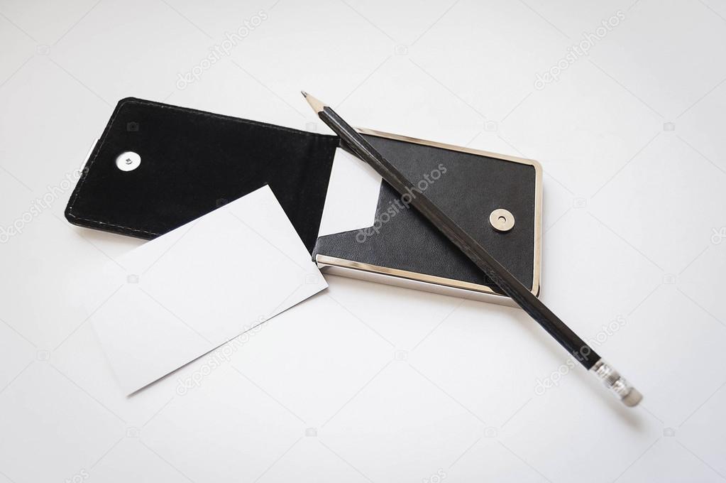 A business card, black card holder and pencil on white background