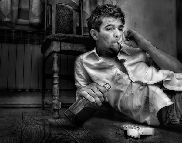 Νεαρός άνδρας, μεθύστακας, κάθεται στο παλαιό δωμάτιο — Φωτογραφία Αρχείου