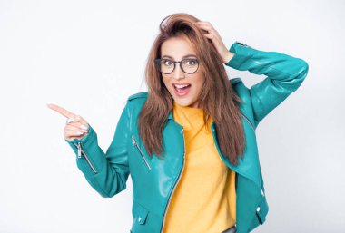 Mesajınız ya da resminiz için işaret parmağıyla işaret eden, yeşil deri ceketli, beyaz arka planda izole edilmiş genç bir kadın. Biliyorum, bu sır açığa çıktı. Stüdyo çekimi