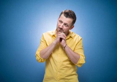 Nostalji konsepti. Sıkıcı genç adam mavi arka planda, sarı gömlekli. Stüdyo çekimi