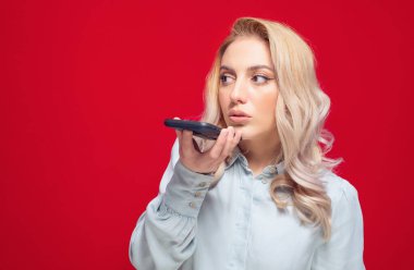 Telefonda genç bir kadının profili var, kırmızı arka planda izole edilmiş. Akıllı telefondan konuşan bir kadın. Stüdyo çekimi