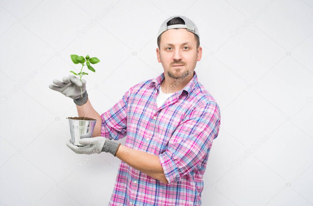 Male gardener holding plant over soil in pot on palms. New life and growth concept, isolated on white background. Male farmer. Studio shot