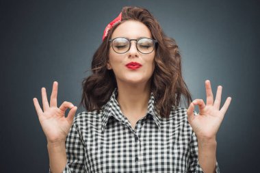 Konsantrasyon ve keyif. Gözleri kapalı genç bir kadın, koyu gri arka planda eğlenirken parmağıyla mükemmel bir işaret sergiliyor. Vücut dili kavramı. Stüdyo çekimi