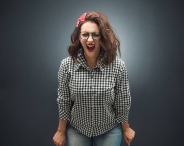 Öfkeli kadın kameraya bakıyor ve koyu gri arkaplanda çığlık atıyor. Siyah arka plan. Hüsrana uğramış kız. Stüdyo çekimi