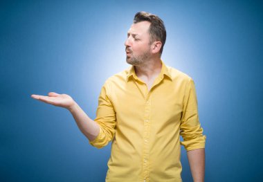 Mavi arka planda seni öpen, sarı gömlekli hoş bir genç görüyorum. Yakışıklı, sevimli bir adam onu öpüyor ve avuç içini gösteriyor, mesaj için fotokopi odası. Stüdyo çekimi