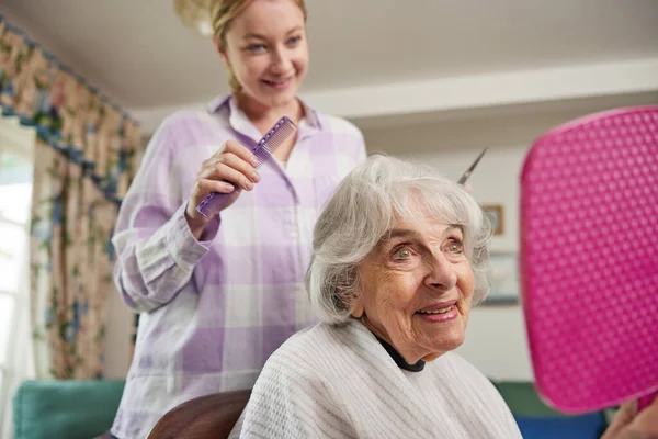 女性流动理发师在家中为老年女性剪头发 — 图库照片