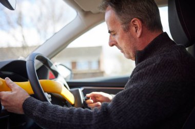 Mature Man Fitting Manual Steering Wheel Lock In Car