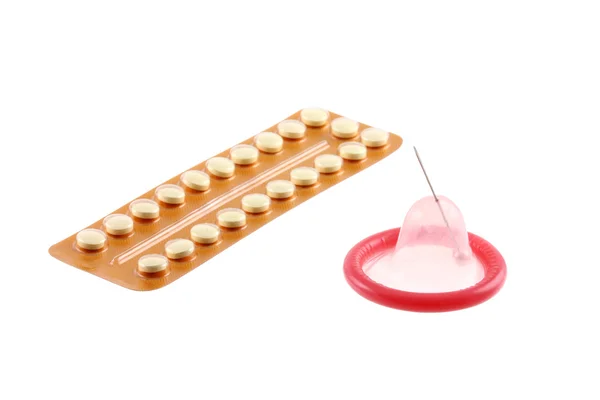 Ehkäisypillerit ja kondomi, jossa on neulan reikä — kuvapankkivalokuva