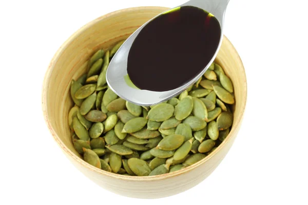 Olio di semi di zucca sopra una ciotola di semi di zucca arrosto — Foto Stock
