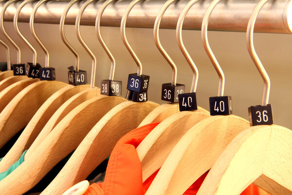 Wooden hangers showing different clothing size tags