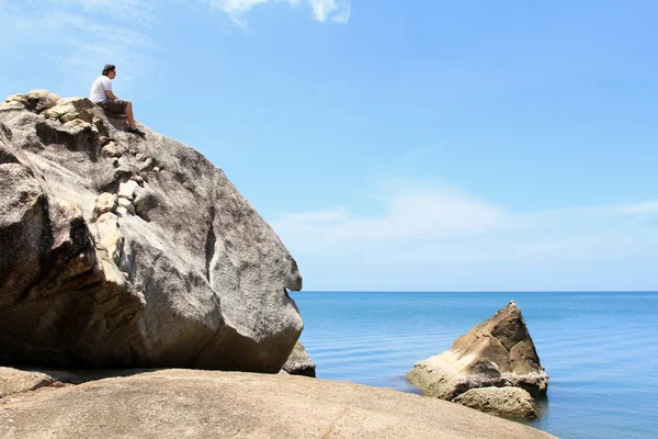 A Man sitting alone on a big rock, by the Tropical Beach — Stock Photo, Image