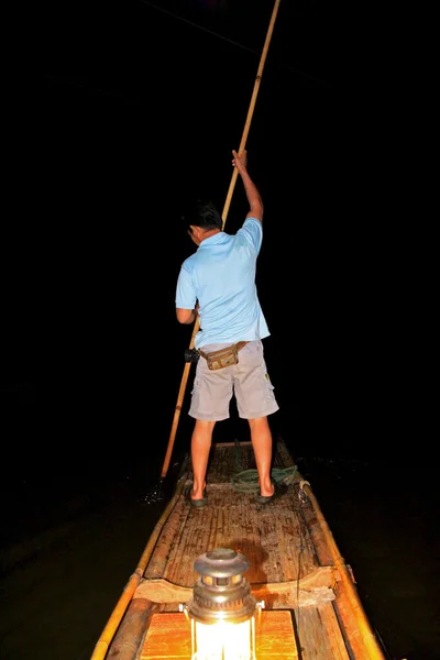 A man standing on a bamboo raft in Maehongson Province, Thailand