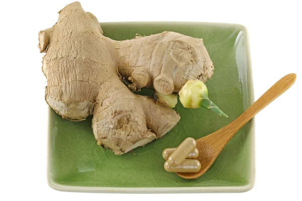 Ginger root capsules next to ginger rhizome root with sprout — Stock Photo, Image