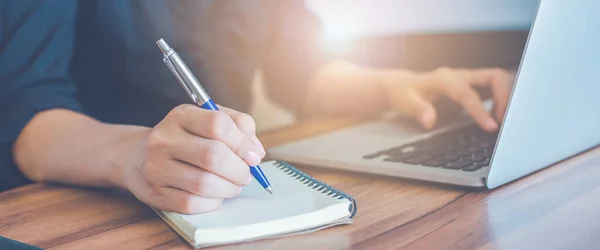 İş kadını bir not defterine kalemle el yazısı ve ofisteki dizüstü bilgisayarı kullan. Web afişi için..