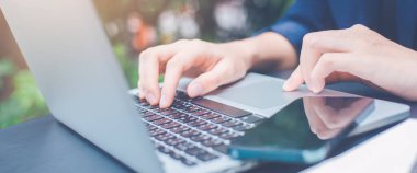 Dizüstü bilgisayarla çalışan ve ofiste cep telefonu kullanan bir kadın. Web pankartı..