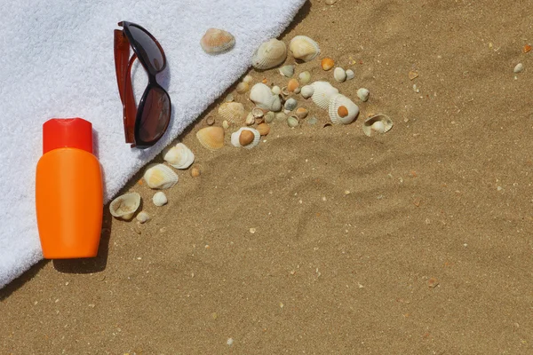 Occhiali da sole e crema solare sul telo mare — Foto Stock