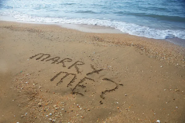Женись на мне, написанной на песчаном пляже — стоковое фото
