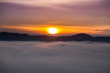 Puslu dağlardaki sisli bulutların üzerinde sabah turuncu güneş ışınları, turuncu ve mor ufuk, Ukrayna