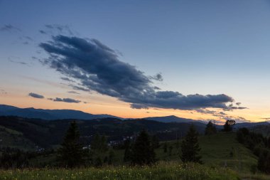 Dağlarda pembe ve mor gün batımı. Ufukta ağaçlar, Karpatlar