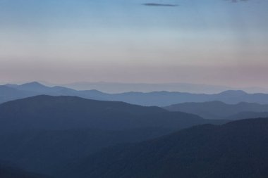 Karpatlar 'da, Chornohora' da, Ukrayna 'da gün batımında dağ tepeleri ve otlakların panoranik mavi manzarası