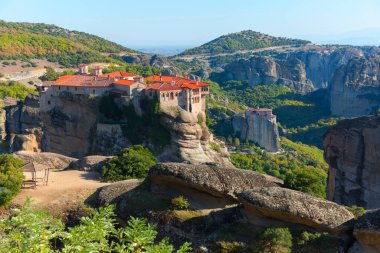 Güzel manzara, Varlaam Ortodoks Manastırı, uçsuz bucaksız monolitik sütun, Meteora, Pindos Dağları, Teselya, Yunanistan, Avrupa 'daki taş duvarın arka planında yeşil yapraklar.