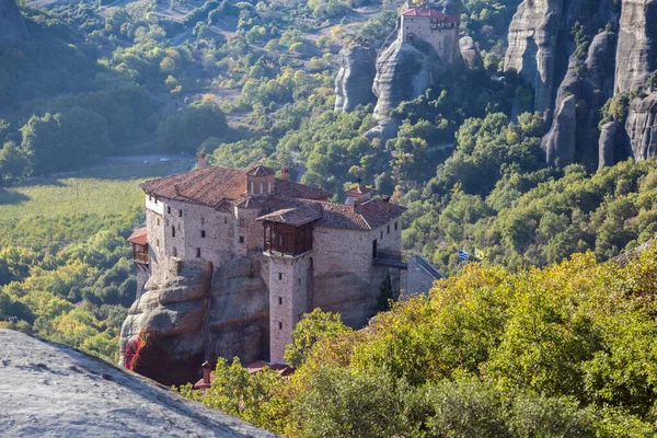 Beautiful scenic view, Orthodox Monasteries of St. Rousanou and St. Nicholas Anapausas, immense monolithic pillar, green foliage at the background of stone wall in Meteora, Pindos Mountains, Thessaly, Greece, Europe