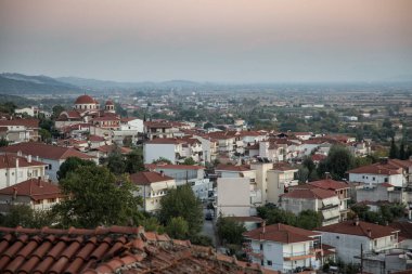 Yunanistan 'ın Kalabaka kentinin günbatımında yukarıdan kiliselere ve beyaz evlerin kırmızı çatılarına bak, Meteora, Yunanistan