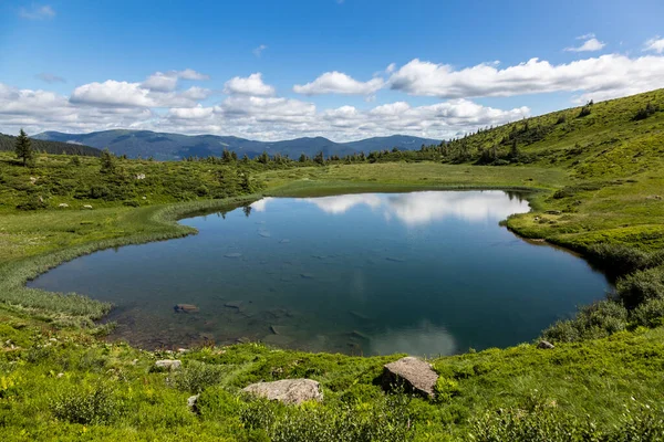 Reflection of the blue sky in the water surface of a mountain lake, Carpathians mountains