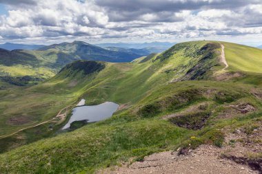 Beautiful mountain landscape among mountain hills and meadow covered green lush grass. Carpathian Mountains, Ukraine