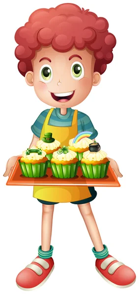 En unga bagare håller en bricka med cupcakes — Stock vektor