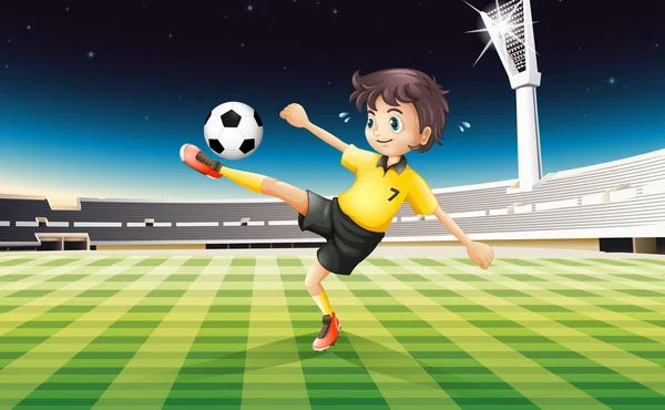 A boy in his yellow uniform playing soccer at the field — Stock Vector