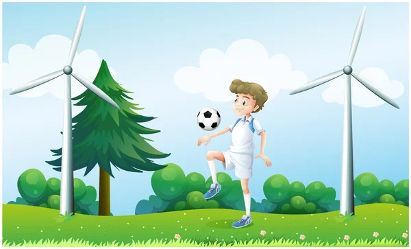 A boy playing football near the windmills — Stock Vector