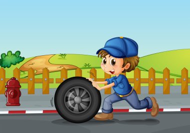 yol boyunca bir tekerlek iterek bir şapka giymiş bir çocuk