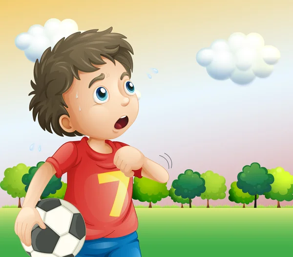 Een jongen houden een voetbal het dragen van een rode shirt — Stockvector