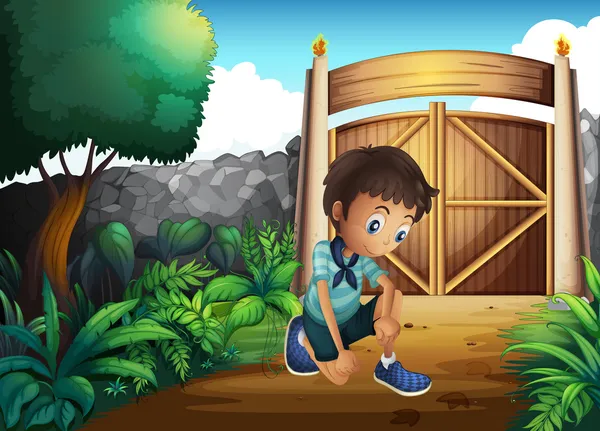En pojke tittar på marken innanför grinden — Stock vektor