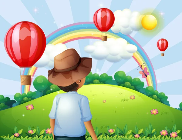 A boy at the hilltop with flying balloons and a rainbow — Stock Vector