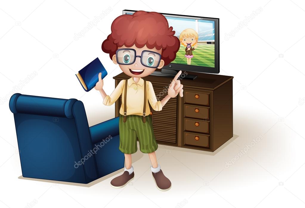 A boy holding a book standing near the blue couch