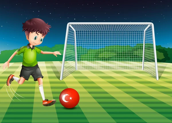 Een jongen die schoppen de bal op het veld met de vlag van Turkije — Stockvector